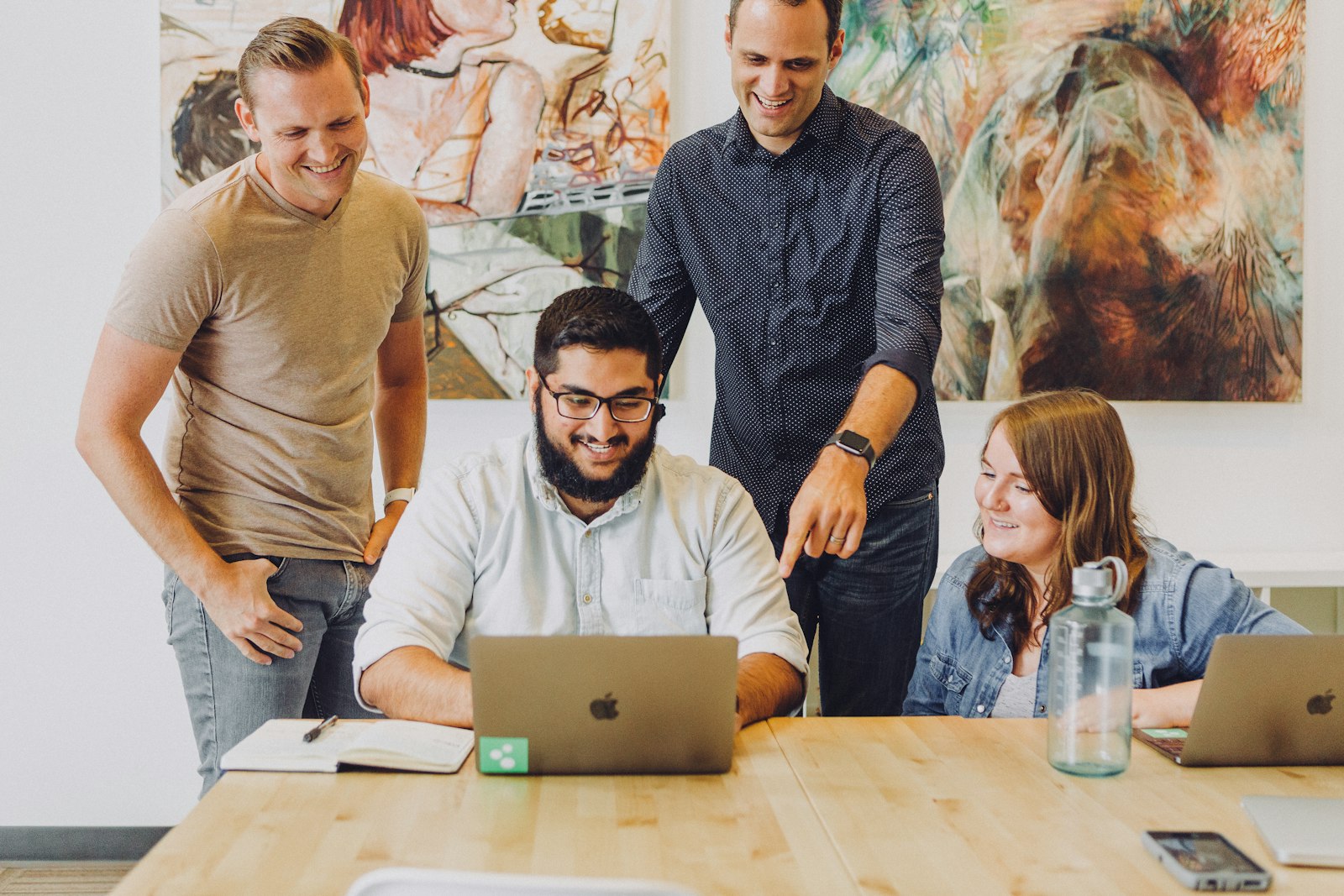 Four coworkers reviewing marketing strategy together around a laptop