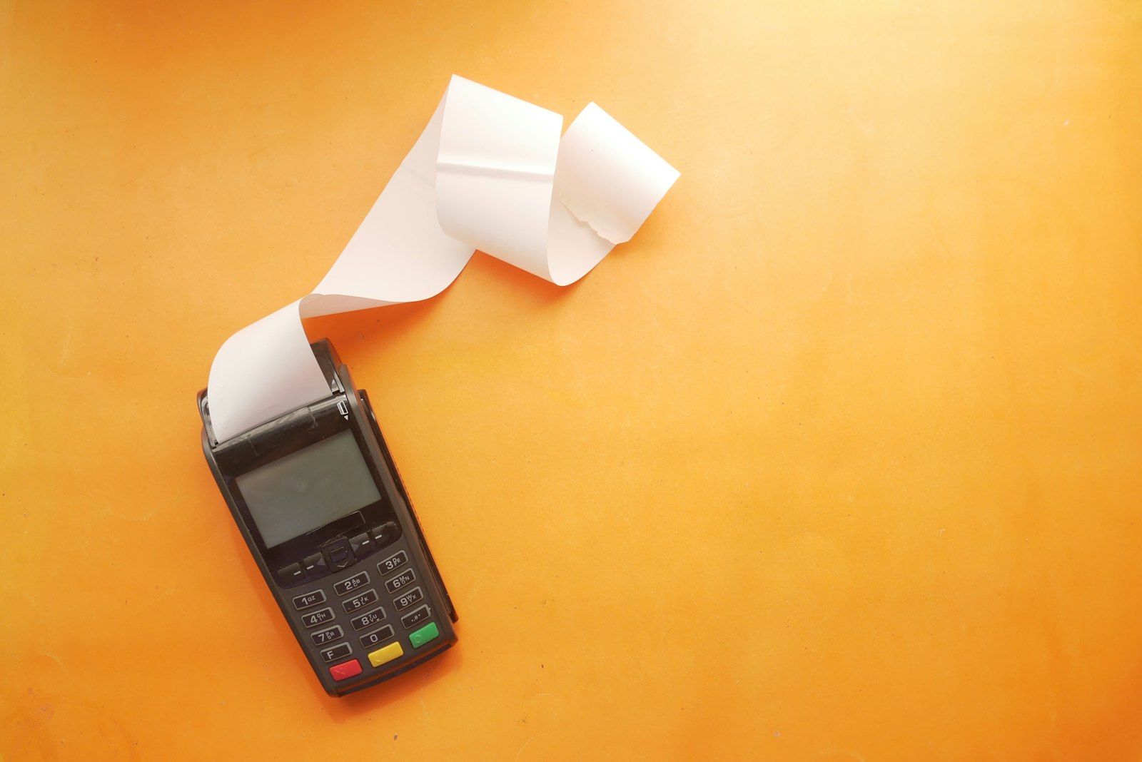 A card payment terminal printing a long paper receipt on an orange background, a reminder that the number on the receipt is what your conversion value should match
