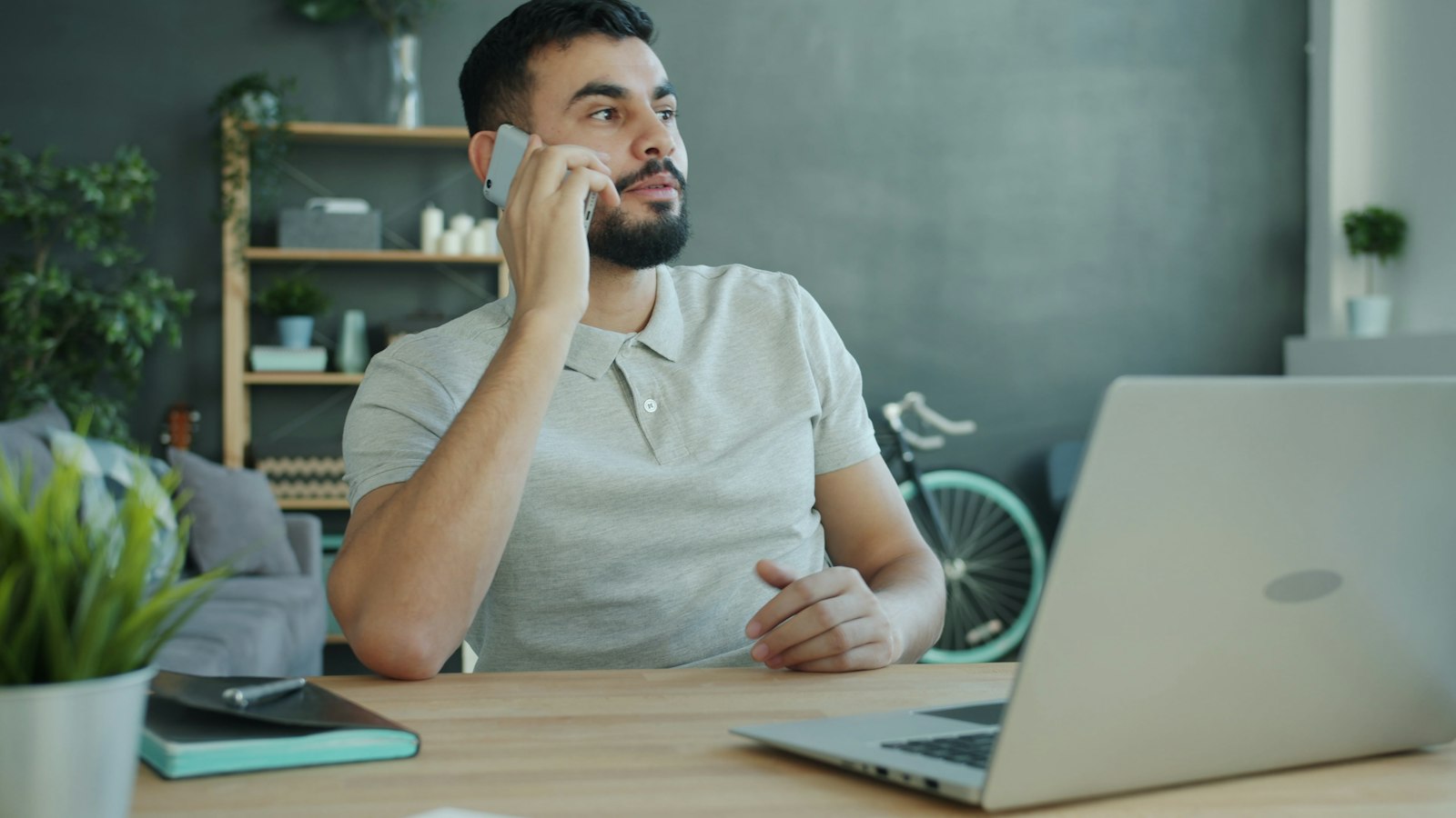 A sales rep at a desk calling a new lead on his phone, laptop open beside him