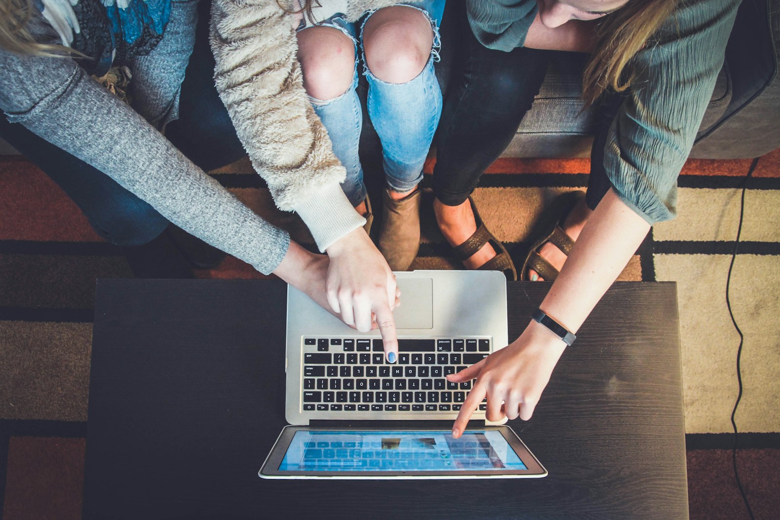 A small team gathered around a laptop reviewing proposed changes together before approving them