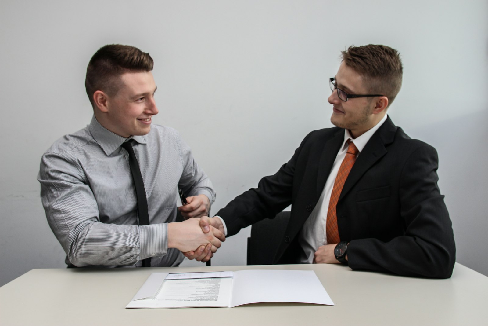 Two people shaking hands across a table, representing choosing and partnering with a marketing agency